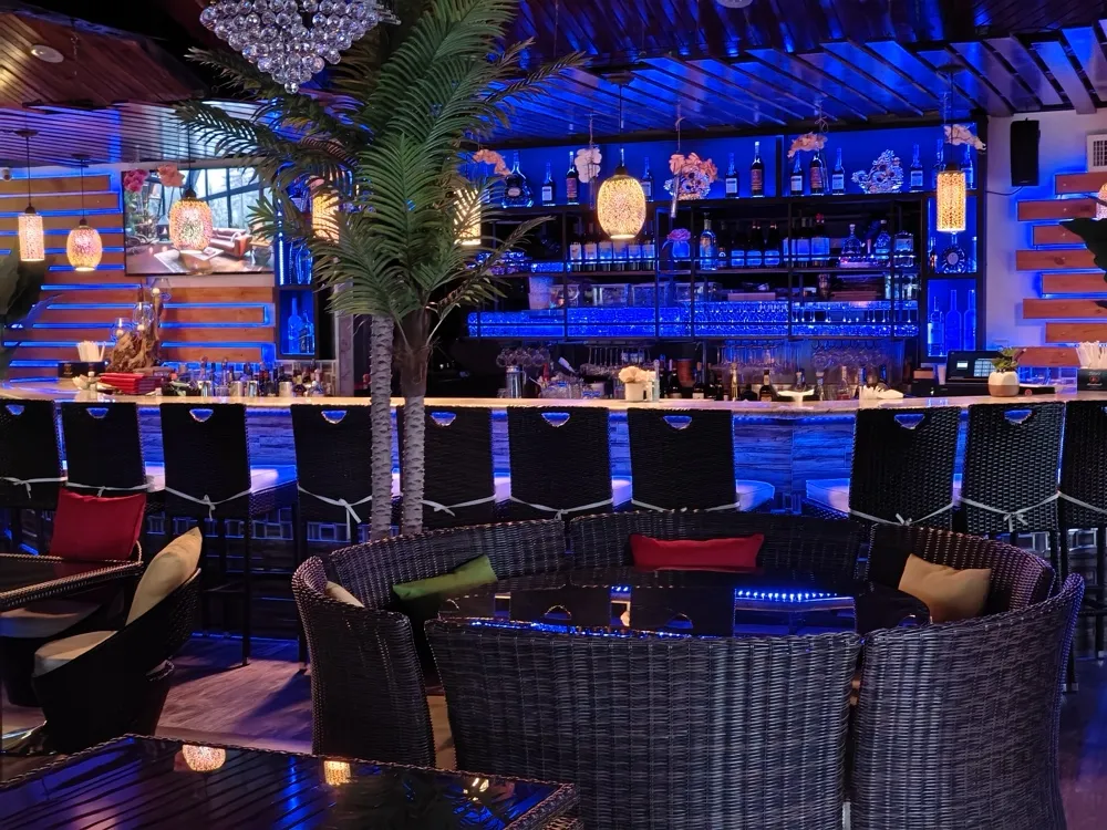 The glowing blue bar with a crystal chandelier and round rattan booth seating
