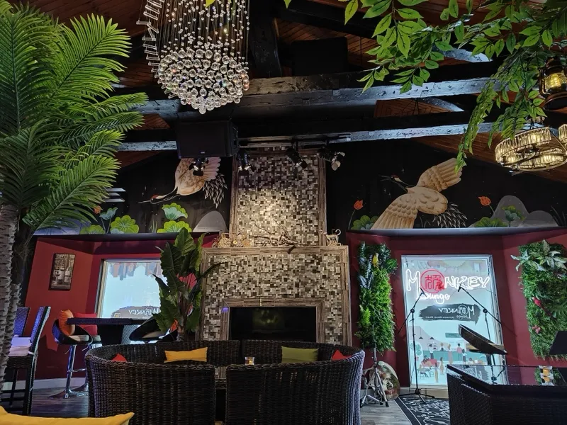 Chandelier-lit lounge with a stone fireplace and tropical plants