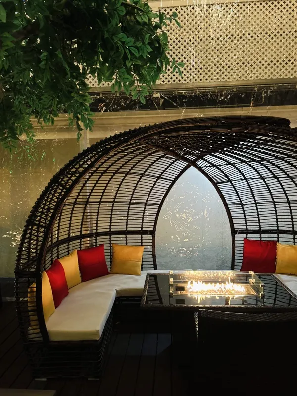 Rattan dome booth with a fire table and gold and red cushions
