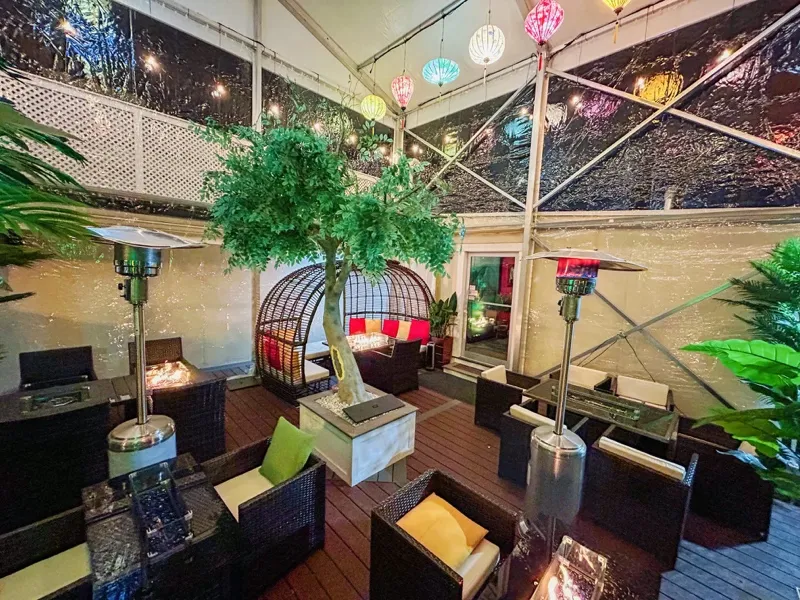 Enclosed patio with colorful lanterns, heaters and a pod booth