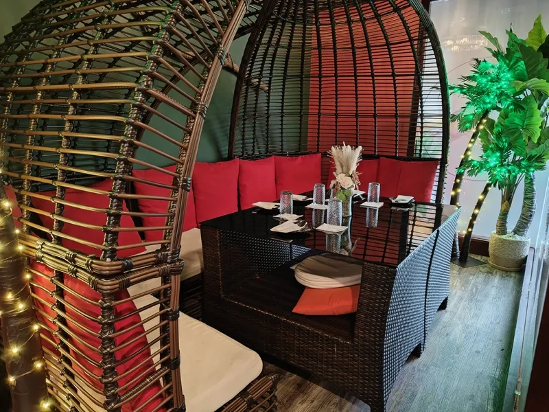 Rattan pod booth with red cushions and string lights